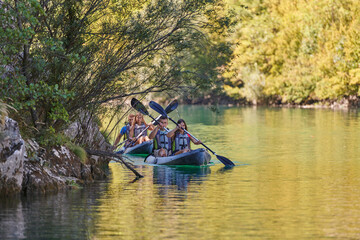 Fototapeta premium A group of friends enjoying having fun and kayaking while exploring the calm river, surrounding forest and large natural river canyons