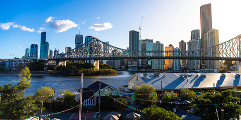 panorama of brisbane city skyline and story bridge at sunset; brisbane cbd and river seen from wilson outlook reserve near kangaroo point during autumn 2023