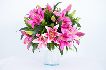 Many kinds of flowers placed in a brightly colored vase in a white setting