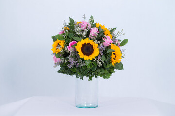 Many kinds of flowers placed in a brightly colored vase in a white setting
