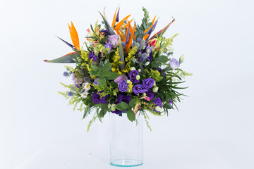 Many kinds of flowers placed in a brightly colored vase in a white setting