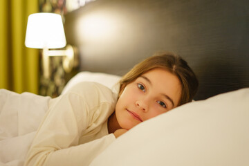 Little cute girl in pajamas sleeping in bed look at camera