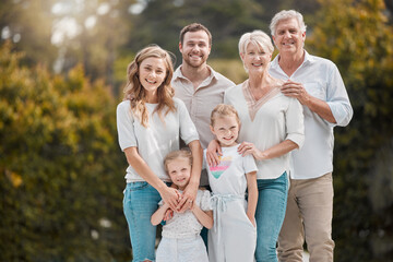 Portrait of a smiling multi generation caucasian family standing close together in the garden at...