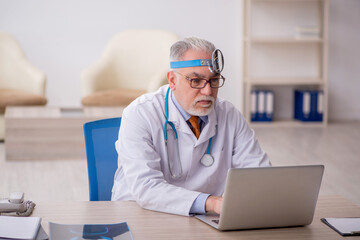 Old male doctor otologist working in the clinic