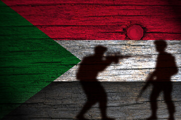 painting of the sudan flag on wood and the shadow of its soldiers.