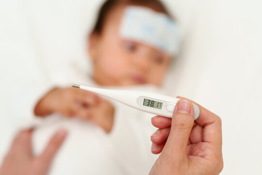 mother measuring temperature of sick baby with cool fever jel pad. displey high fever temperature