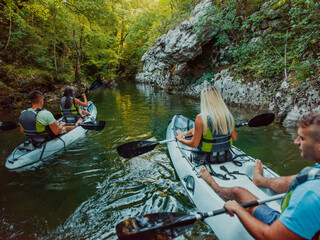 A group of friends enjoying having fun and kayaking while exploring the calm river, surrounding forest and large natural river canyons