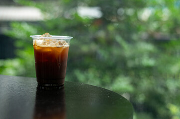 A cup of iced coffee with a clear plastic cup sits on a table in a cafe