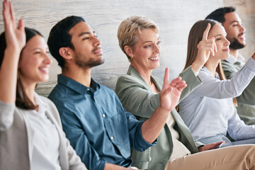 We have questions. Shot of a diverse group of businesspeople sitting in a row and raising their...