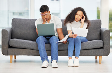 Fototapeta premium Can we unsubscribe from being adults. Shot of a young couple using a laptop while going through paperwork at home.
