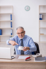 Old male employee drinking coffee during break