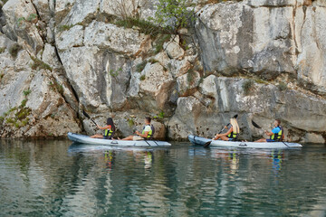A group of friends enjoying having fun and kayaking while exploring the calm river, surrounding forest and large natural river canyons