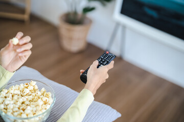 Asian woman Watching smart TV and using remote controller Hand holding television audio remote control at home with the remote control television