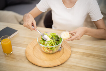 Happy beautiful Asian woman eating healthy food with vegan.salad in the kitchen at home.