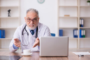 Old male doctor drinking coffee during break