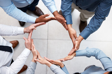 Round and round we go. Shot of a group of unrecognizable businesspeople forming a circle with their...