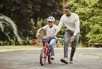 Were standing tall. Shot of an adorable boy learning to ride a bicycle with his father outdoors.