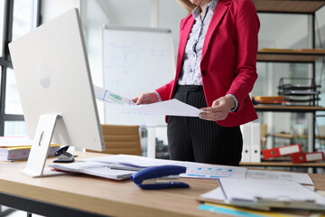 Woman studies investigation papers standing at table