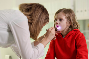 Doctor checks throat of patient illuminating with flashlight