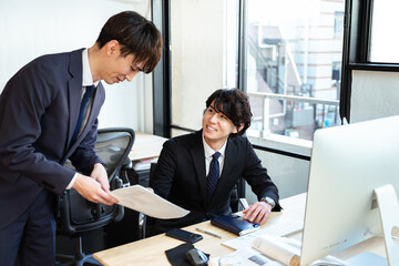オフィスで笑顔で仕事をする職場にいる中小企業に務めるの男性2人