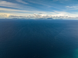 Blue sea with island and blue sky with clouds. Flight over the sea. Indonesia.