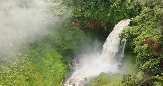 Aerial drone of waterfall in the green forest. Telun Berasap Falls in the jungle. Sumatra, Jambi, Indonesia.