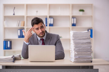 Young male employee unhappy with excessive work in the office