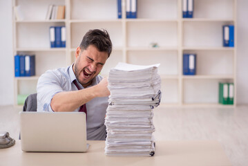 Young male employee unhappy with excessive work in the office