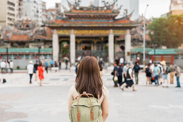 woman traveler visiting in Taiwan, Tourist with hat sightseeing in Longshan Temple, Chinese folk religious temple in Wanhua District, Taipei City. landmark and popular. Travel and Vacation concept