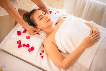 Obraz na płótnie Canvas The bed is decorated with soft rose petals and the room is filled with relaxing aromas good for massage.