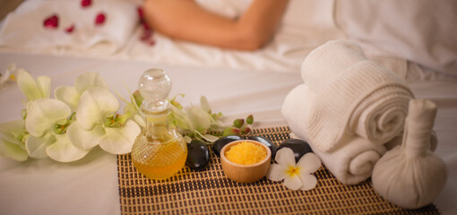 Beautiful asian woman getting massaged by professional masseuse lying on white bed preparing to massage with focus oil in glass bottle and towel.