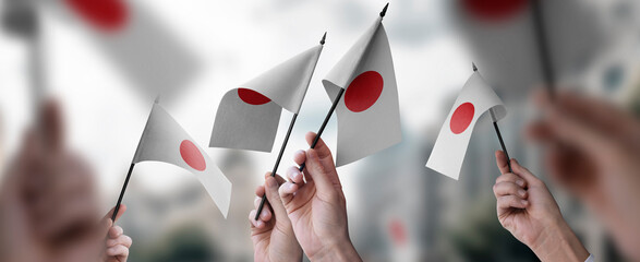 A group of people holding small flags of the Japan in their hands