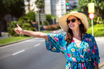 Young female tourist trying to stop a car with thump up. Hitch hiking. Traveling by autostop.