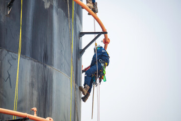 Focus top view male worker down height tank roof rope access safety inspection of thickness storage tank .