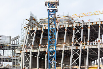 Construction of a large concrete building. Construction crane on the background of the sky. Construction site. 