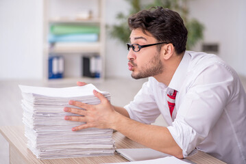 Obraz premium Young male employee and too much work in the office