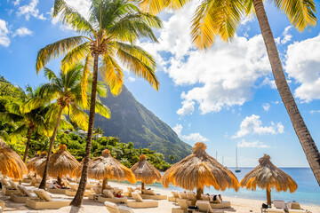 Caribbean beach with palms and straw umrellas on the shore with Gros Piton mountain in the background, Sugar beach, Saint  Lucia - obrazy, fototapety, plakaty
