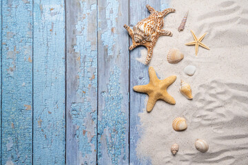 Summer, beach and vacation concept with free text space. Top view. Flat layout with a large sea star and sea shell and various sea shells and fine beach sand on an old blue wooden boards background