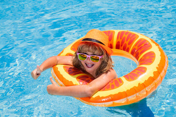 Child in sunglasses and summer hat floating in pool. Kids summer vacation. Children floating in water pool. Children playing and active leisure, swimming pool concept.