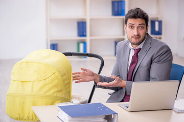 Young male employee looking after newborn at workplace