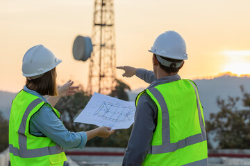 Professional team Engineer managers workers working outdoors with telecommunication antenna and sunset background..