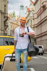 Portrait of fashion man with luggage, suitcases going on vacations. Travel lifestyle. Tourist businessman traveling in european city. Confident rich man traveling in european city.