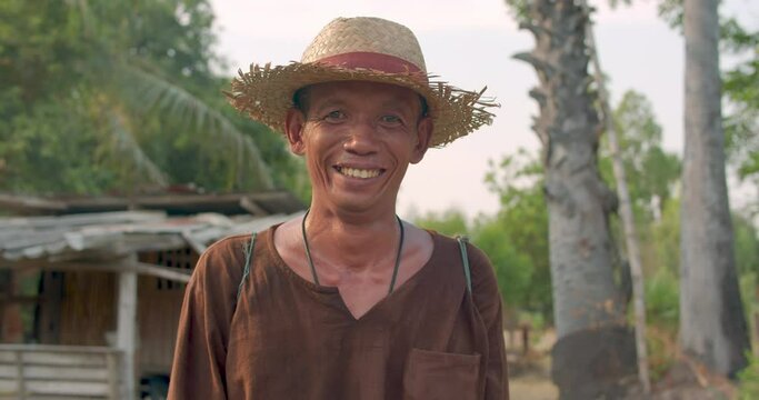 An Asian man who is poor farmer standing in palmyra palm (toddy palm) garden that he will harvest the fresh sugar and fruits in the rural area.