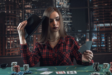 attractive girl looks at the cards to make a bet or pass at poker game