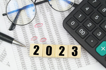 Round eyeglasses, pen, calculator and cubes with numbers 2023. 