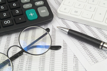 White and black calculators, glasses and pen on financial bills. Accountancy and arbitrage concept.
