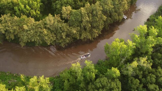 A stream in the Amazon rainforest at sunset with a passing tourist boat. Top view down