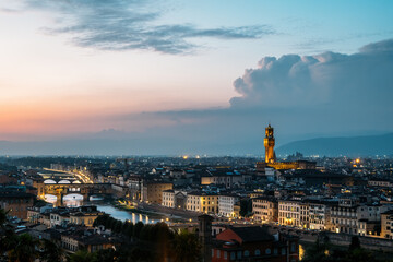 Top view of the Old Palace in Florence Town Hall tower by architect Arnolfo di Cambio in a warm summer late evening overlooking the bridge over the Arno river. Copyspac