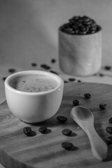 A cup of coffee with coffee beans with blurred background and black and white effect