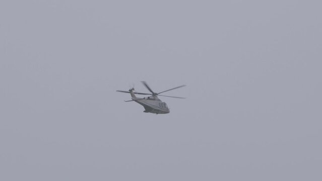 A grey helicopter against a cloudy sky.